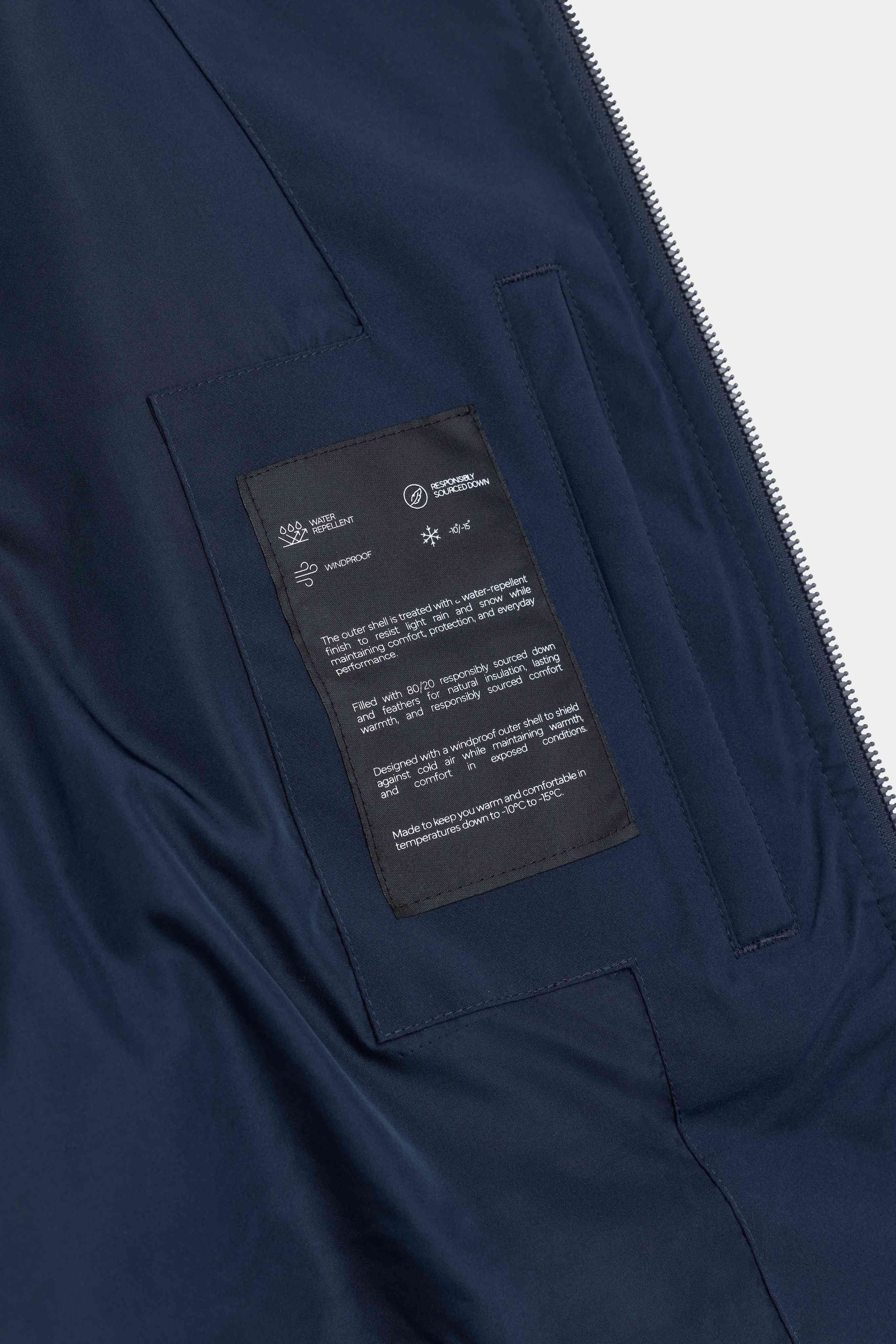 Interior details and technical feature label inside the navy CASPARA Boreal Puffer Jacket.